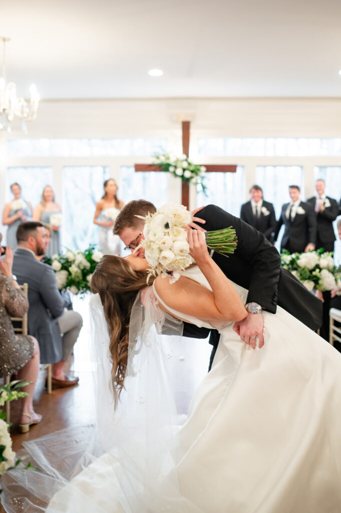 A bride and groom kissing as they walk down the aisle on their wedding day at Primrose Cottage in Roswell Georgia